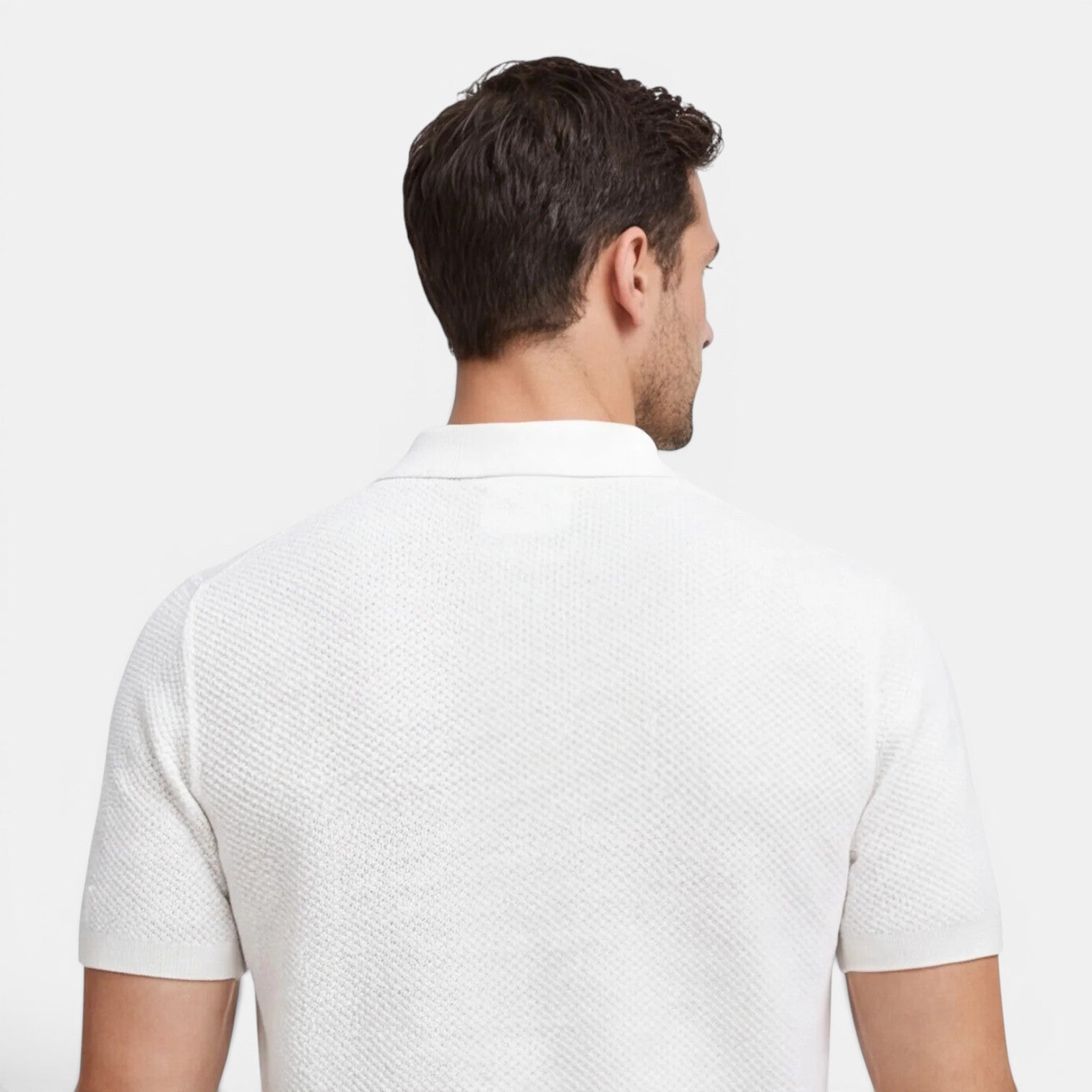 Man wearing a white textured polo shirt on a light gray background