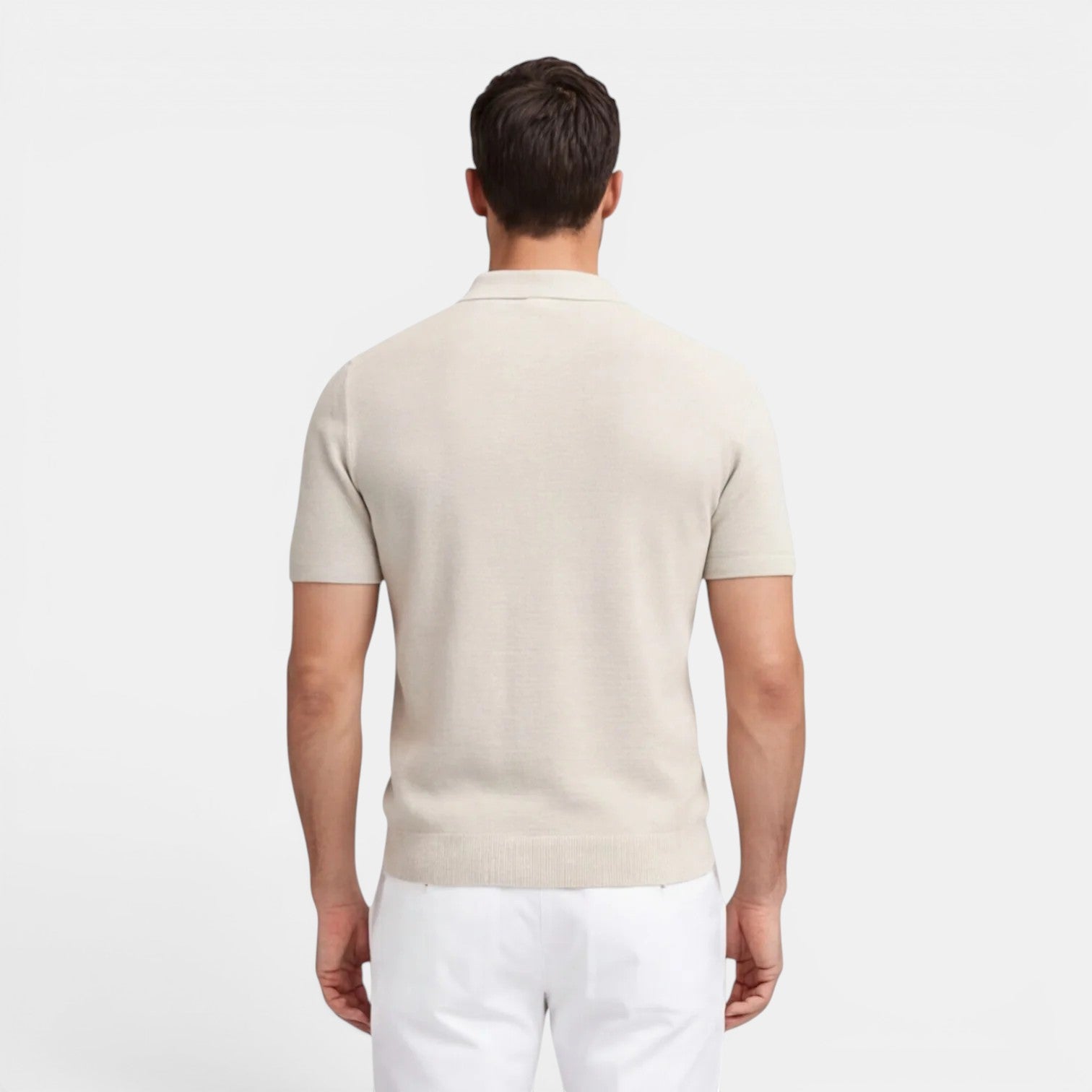 Man wearing a beige polo shirt and white pants on a light gray background