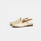 Pair of cream-colored loafers with a strap on a light gray background