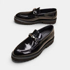 Pair of black glossy loafers on a white background