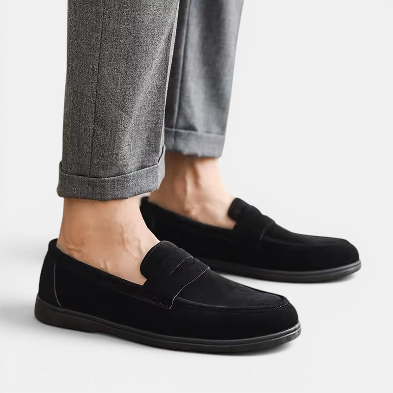 Black loafers worn with gray pants on a light background