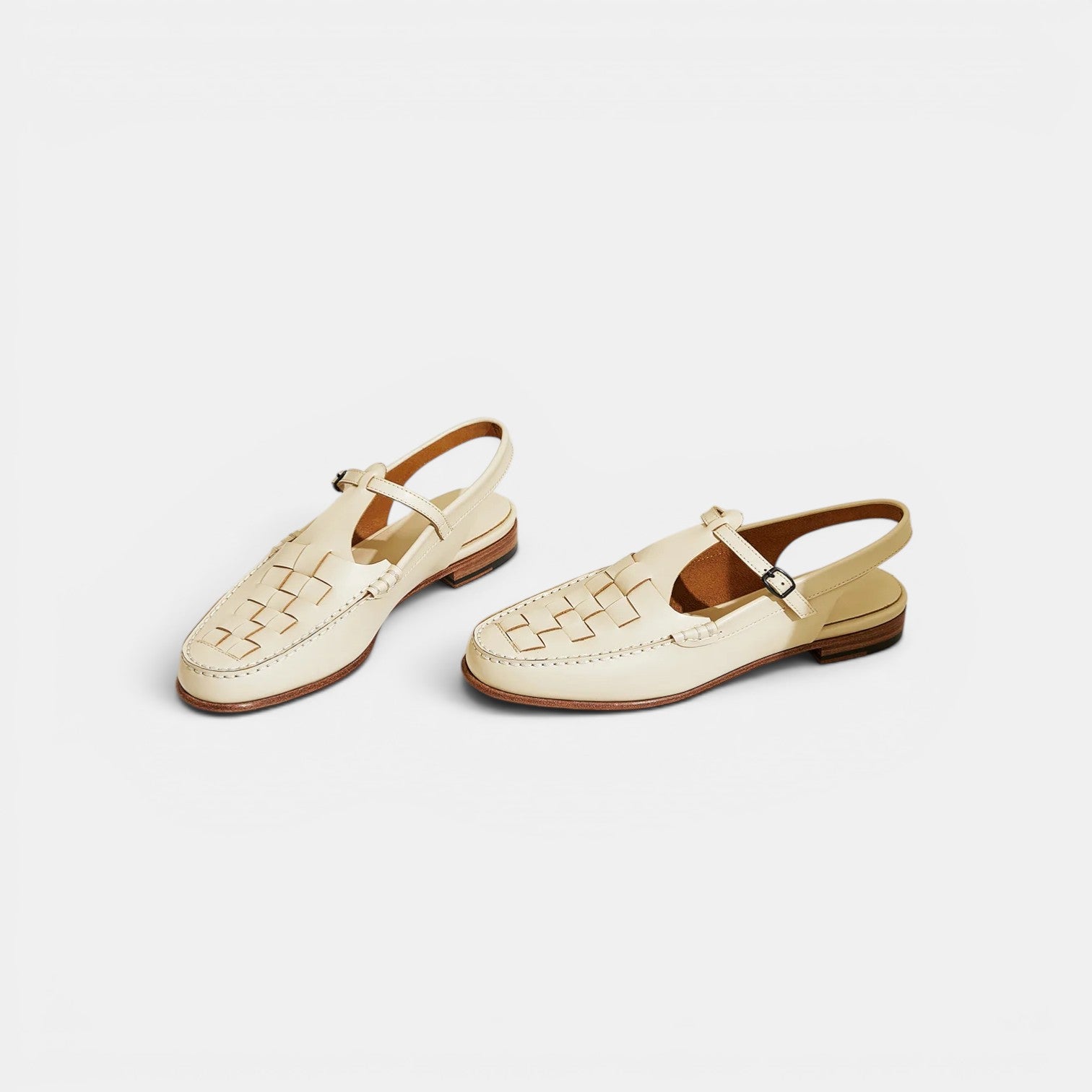 Pair of cream-colored sandals with woven design on a white background