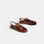 Pair of brown leather sandals on a light gray background