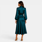 Woman wearing a teal satin dress on a white background