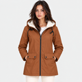 A woman wearing a brown hooded jacket with a cream sherpa-lined hood, black drawstrings, and front flap pockets, photographed against a light gray studio background.