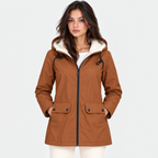A woman wearing a brown hooded jacket with a cream sherpa-lined hood, black drawstrings, and front flap pockets, photographed against a light gray studio background.