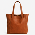 A medium brown leather tote bag with dual top handles and a front slip pocket, shown against a plain white background.