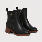 A pair of black leather ankle boots with side zippers, a low stacked block heel, and a brown sole, shown on a light gray background.