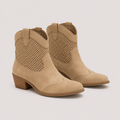 A pair of beige western-style ankle boots with perforated side panels and low stacked block heels, shown on a light gray background.