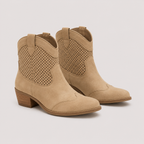 A pair of beige western-style ankle boots with perforated side panels and low stacked block heels, shown on a light gray background.