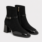A pair of black ankle boots with a mix of matte suede and glossy patent leather, featuring a block heel, pointed toe, and side zipper.