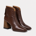 A pair of dark brown leather ankle boots with a chunky block heel, shown from a three-quarter angle on a light gray background.