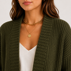 A close-up of a woman wearing an olive green ribbed knit cardigan over a white top, accessorized with layered gold necklaces.