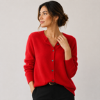A woman wearing a bright red knit button-front cardigan sweater with a V-neck, paired with black pants, photographed against a plain light gray studio background.