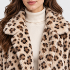 Close-up of a woman wearing a plush faux-fur coat with a beige, brown, and black leopard print over a cream ribbed turtleneck sweater.