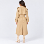 A woman shown from the back wearing a classic beige trench coat with a matching waist belt, paired with beige heeled boots, against a plain white studio background.