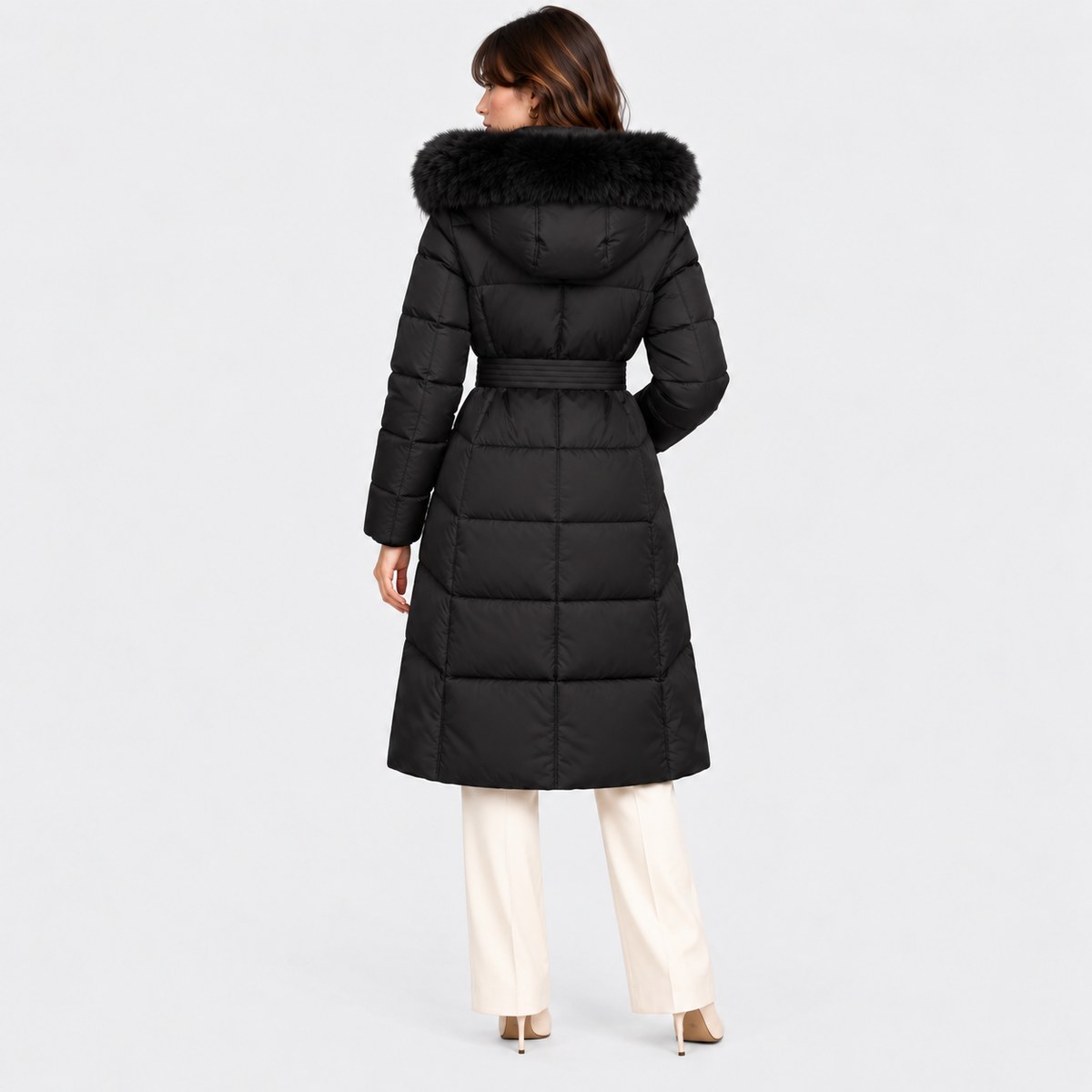 Back view of a women's black long puffer coat with hood and quilted design