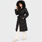 Side view of a woman wearing a black long puffer coat with fur-trimmed hood and waist belt