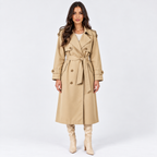 A woman modeling a mid-length beige trench coat with a matching waist tie, shown against a plain light gray studio background.