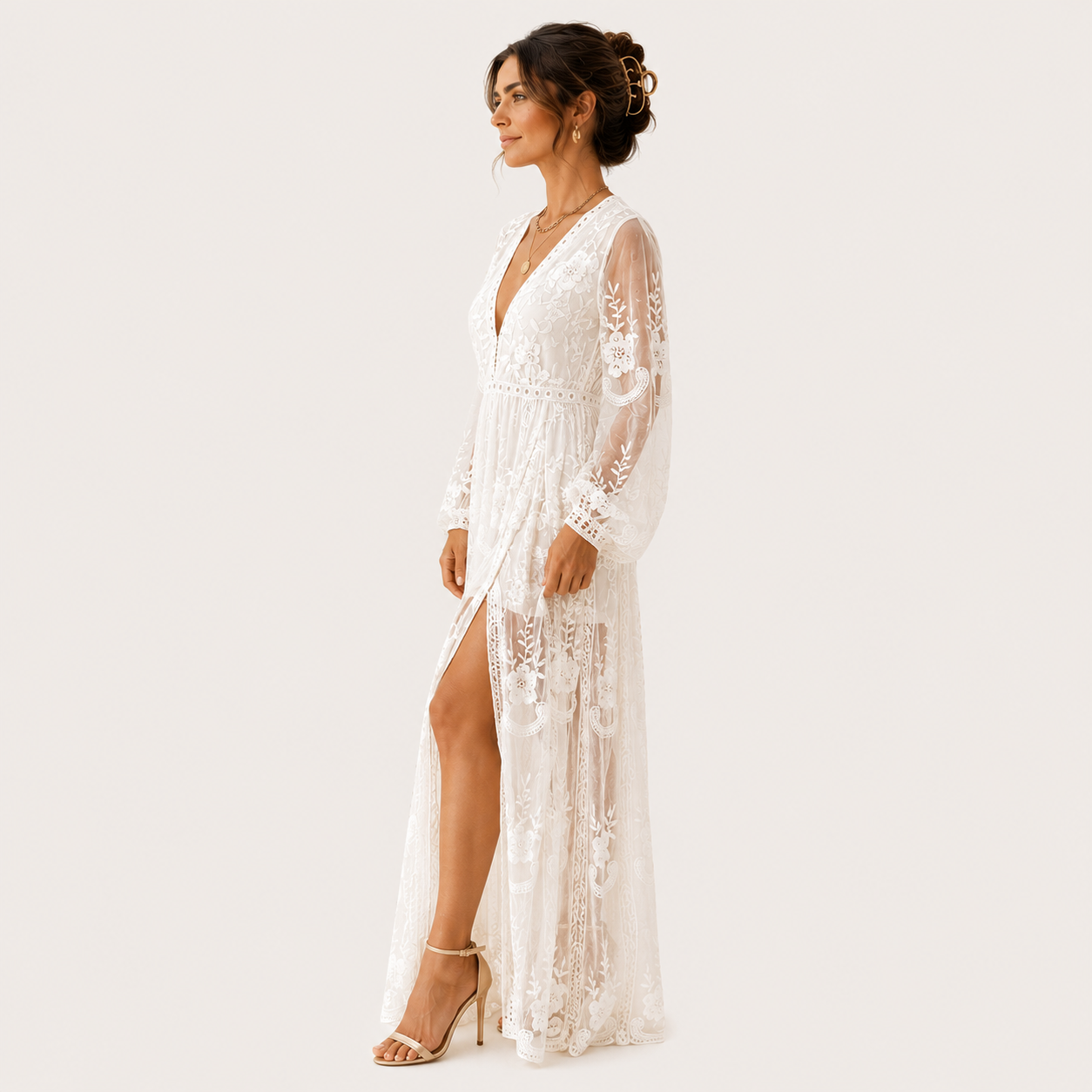 A woman modeling a long white lace maxi dress with sheer long sleeves, a deep V-neckline, and a high thigh slit, shown against a plain light background.