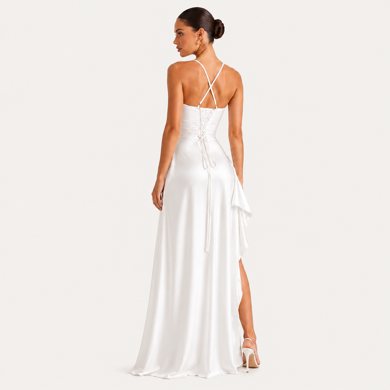 A woman modeling a white satin maxi dress from the back, featuring thin crisscross halter straps, lace-up back detailing, and a draped side detail, set against a solid off-white background.