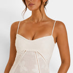 Woman wearing a white dress with thin straps on a plain background
