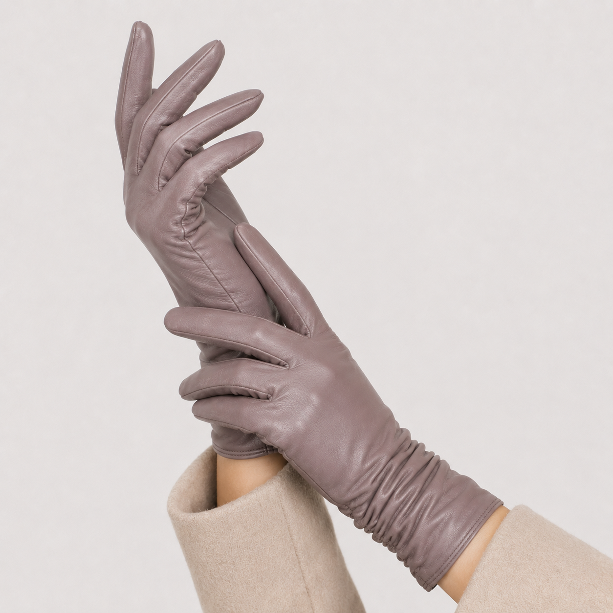 A pair of long, slim gloves in a muted taupe-brown color, worn on hands against a plain light gray background.