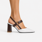 A woman's high-heeled slingback shoe with a white toe and back strap, dark brown straps and block heel, and a small gold buckle, shown on a model's foot against a light gray background.