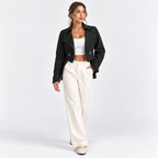 Woman wearing a black double-breasted blazer with gold buttons and white wide-leg pants