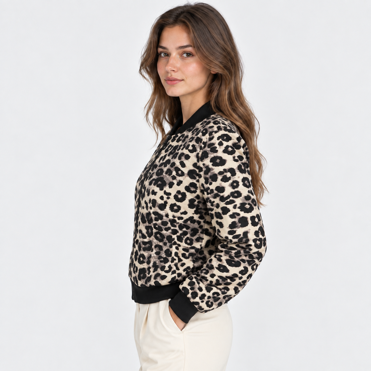 A woman wearing a beige and black leopard print knit sweater with black ribbed trim, shown from a side profile against a light gray studio background.