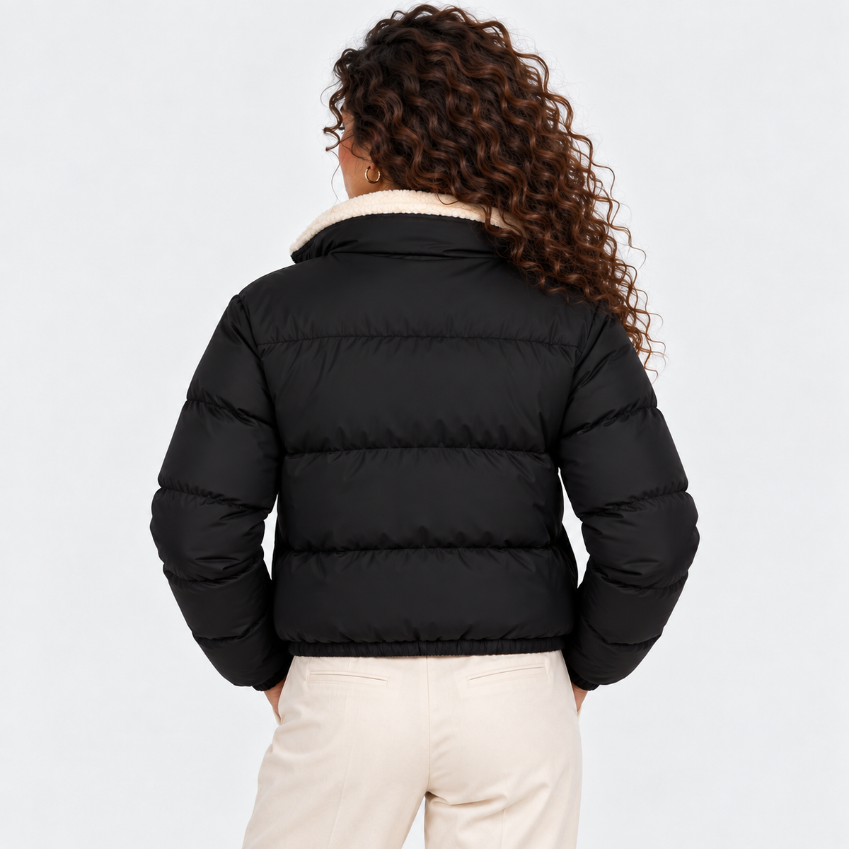 Back view of a woman wearing a black quilted puffer jacket with shearling collar