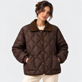 A woman wearing a dark brown diamond-quilted puffer jacket with a matching brown corduroy collar, standing against a light gray studio background.