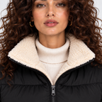 Close-up of black puffer jacket with cream shearling collar and zipper closure
