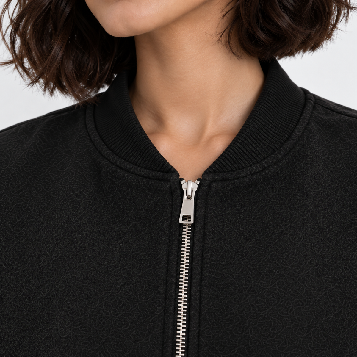 Close-up of women's black bomber jacket with front zipper and ribbed neckline