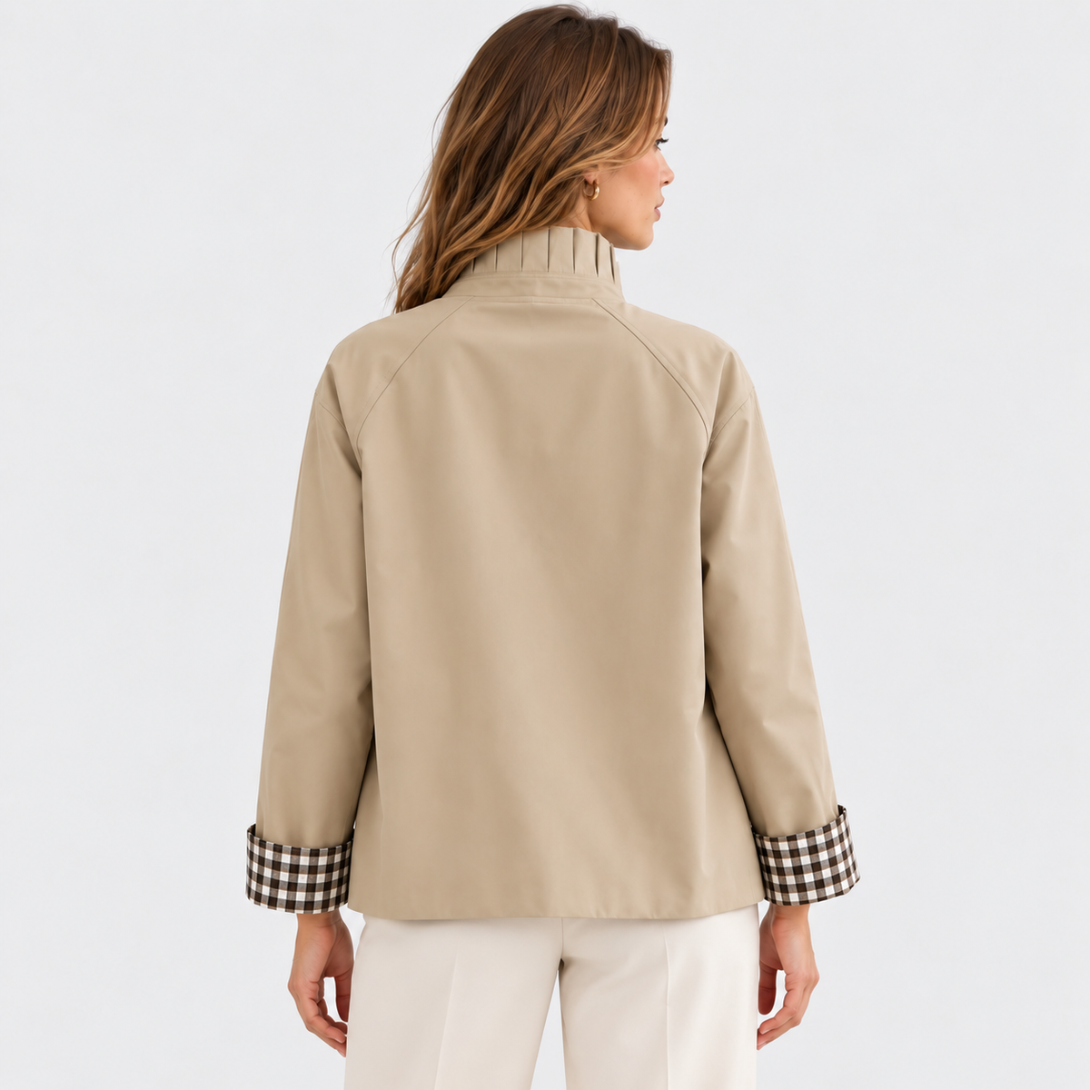 Back view of a woman wearing a beige button-front jacket with white pants