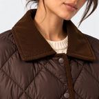 Close-up of a model wearing a brown quilted puffer jacket with a ribbed brown corduroy collar over a cream knit top.