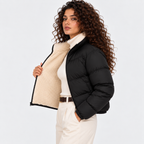 Side view of a woman wearing a black quilted puffer jacket with cream shearling collar