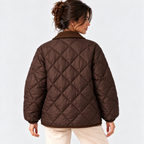 A woman shown from the back wearing a brown diamond-quilted puffer jacket with a matching brown collar, paired with light beige pants, against a plain light gray studio background.