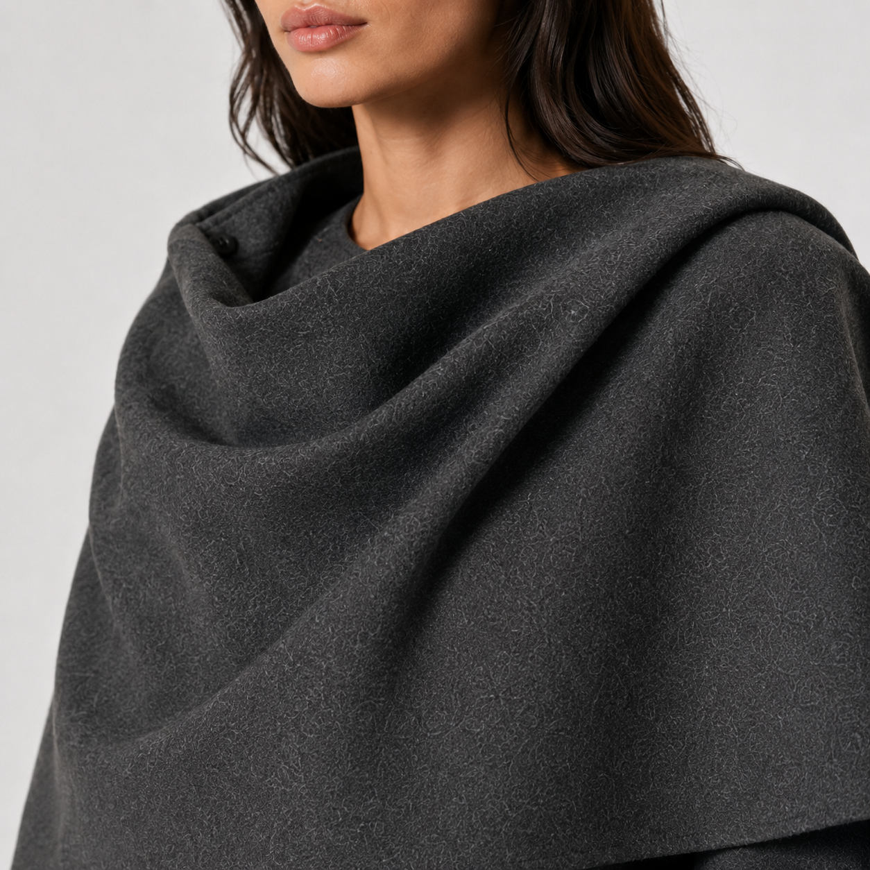 A close-up of a model wearing a dark charcoal gray shawl or wrap with a soft, draped texture.