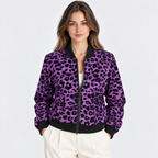 A woman modeling a purple and black leopard-print zip-up bomber jacket with black ribbed collar, cuffs, and hem, paired with cream pants against a light gray studio background.