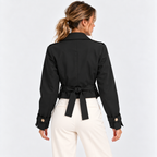 Back view of a woman wearing a black fitted double-breasted blazer with white pants