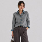 A woman models a gray knit button-up shirt with a blue denim collar, cuffs, and front placket, paired with dark gray wide-leg trousers, against a light gray studio background.