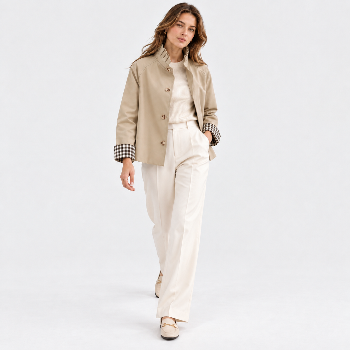 Woman wearing a beige button-front jacket with checked cuffs and white tailored pants