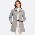 A woman modeling a light gray wool-blend coat with large decorative buttons, worn over a cream turtleneck and cream pants against a plain white studio background.