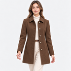 A woman modeling a brown wool-blend coat with a collar and decorative buttons, worn over a cream turtleneck and cream pants against a light gray studio background.