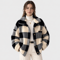 A woman models a black and cream checkered fuzzy cropped jacket over a cream turtleneck and cream trousers, against a light gray studio background.