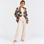 Woman wearing a brown and black plaid blazer with white tailored pants