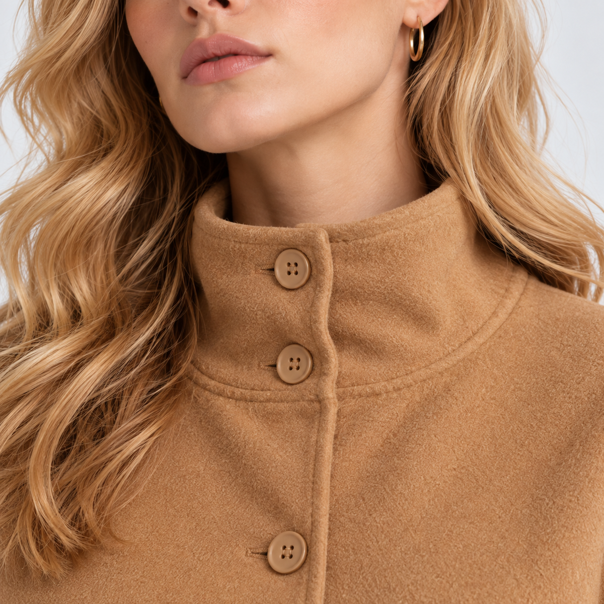 Close-up of women's camel brown cape coat with stand collar and button closure