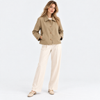 Woman wearing a beige button-front jacket with white tailored pants