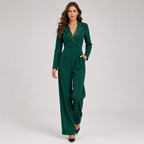 A woman modeling a dark green wrap-style blazer jumpsuit with wide legs, shown against a plain light gray studio background.